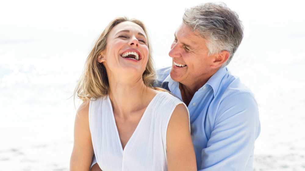 Happy couple laughing together at the beach | What Is Nicotinamide Riboside? What Does It Do? | nicotinamide riboside | nicotinamide riboside benefits | Featured