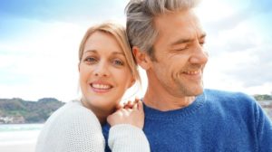 Middle-aged couple embracing each other at the beach | Featured