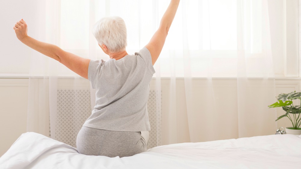 senior woman sitting on bed | Better Than An Anti-Aging Drug: Your Own Genetics | anti aging drug | aging gracefully tips | Featured